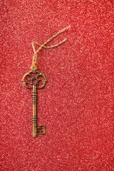 vintage golden key on blurred glittering red abstract background. creative concept of love, happiness, Valentines day. copy space. shallow depth, soft selective focus