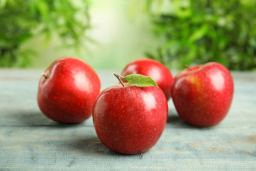 Ripe juicy red apples on blue wooden table against blurred background. Space for text