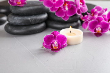 Fototapeta na wymiar Spa stones, orchid flowers and candle on grey background
