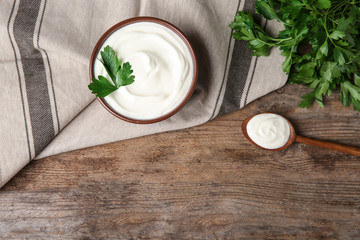 Flat lay composition with sour cream and parsley on wooden table, space for text
