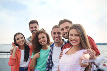 Happy young people taking selfie outdoors on sunny day