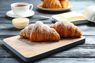 Board with tasty croissants on dark wooden table. French pastry