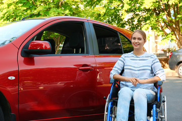 Young woman in wheelchair near car outdoors