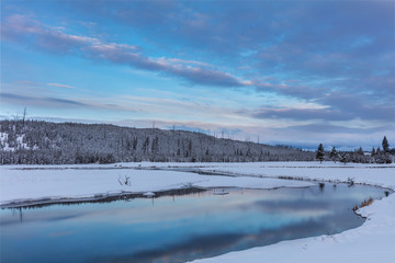 Fototapeta na wymiar Sunrise clouds reflecting into the Madison River in winter in Yellowstone National Park, Wyoming, USA