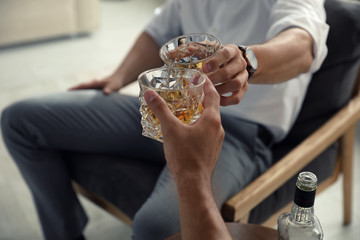 Young men drinking whiskey together at home, closeup