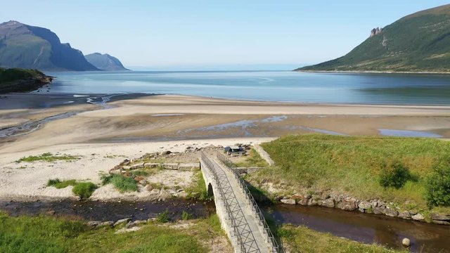 Aerial drone shot flying over a wooden bridge on an arctic sandy beach. Low tide in Scandinavia.