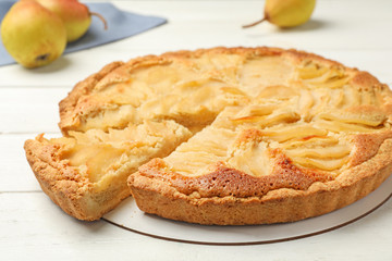 Cut delicious sweet pear tart on white wooden table, closeup