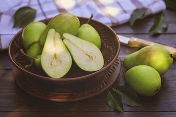 fresh green ripe pears in the bowl close-up. background with pears in the garden.
