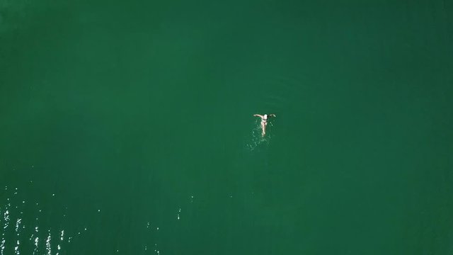 Drone shot woman back floating on a azure lake