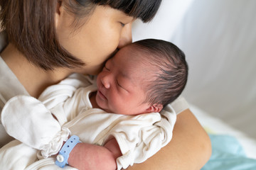 Asian mother kissing her newborn baby