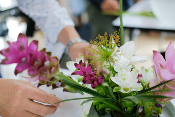 Obraz na płótnie Canvas florist arranging flower bouquet in vase. floristry class course workshop