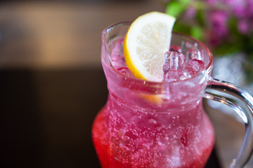 Summer iced drink with lemon dipping in red juice.