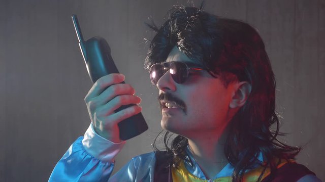 A funny-looking guy from the 70s 80s using a walkie talkie to communicate