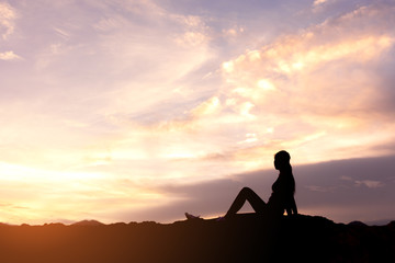 silhouette woman sitting and relaxing on top of mountain