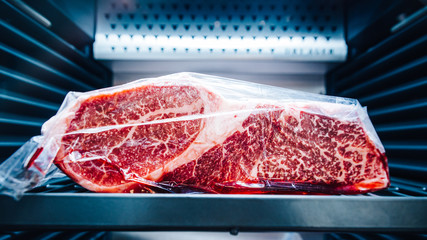 Close-up Premium Rare Sirloin Wagyu A5 beef with high-marbled texture that wrap with plastic inside refrigerator.