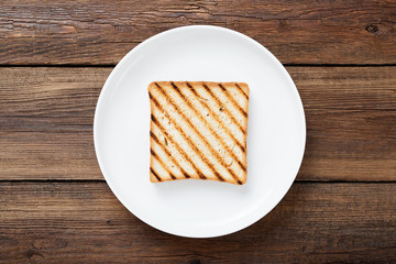Slice of toasted bread on wooden background.