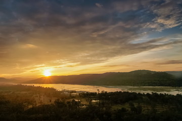 Mountain view evening above Mekong river around with the hills and yellow sun light in cloudy sky background, sunrise at Pha Taem View Point, Pha Taem National Park, Ubon Ratchathani, Thailand.