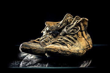 Close up of very dirty sneakers fully in mud isolated on black background. - 284482314
