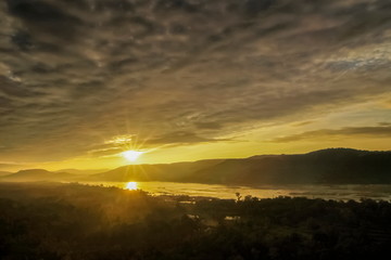 Fototapeta na wymiar Mountain view morning above Mekong river around with the hills and yellow sun light in cloudy sky background, sunrise at Pha Taem View Point, Pha Taem National Park, Ubon Ratchathani, Thailand.
