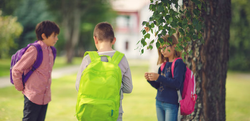 Obraz premium Children with rucksacks standing in the park near school