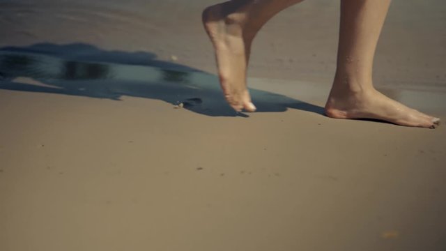Female Legs Walk Along The Sandy Beach.Woman Feet Walking On Golden Sand At Sunset Close Up.Legs Of Girl Stepping And Relaxing On Sandy Coast.Woman Going On Sandy Shore In Hot Summer Day On Vacation.
