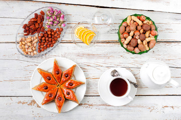 Traditional Azerbaijan holiday Novruz cookies baklava on white plate on the white background with nuts and shakarbura,tea,lemon,kata,mutaki,flat lay,top view,space for copy