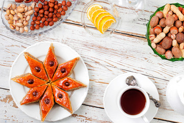Traditional Azerbaijan holiday Novruz cookies baklava on white plate on the white background with nuts and shakarbura,tea,lemon,kata,mutaki,flat lay,top view,space for copy