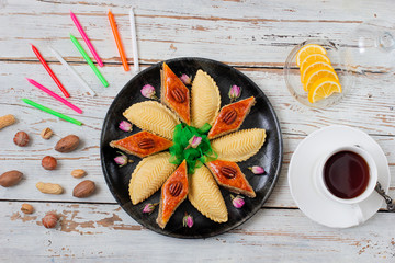Traditional Azerbaijan holiday Novruz cookies baklava on white plate on the white background with nuts and shakarbura,tea,lemon,kata,mutaki,flat lay,top view,space for copy