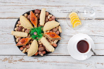 Traditional Azerbaijan holiday Novruz cookies baklava on white plate on the white background with nuts and shakarbura,tea,lemon,kata,mutaki,flat lay,top view,space for copy