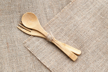 Set of wooden bamboo cutlery: fork and spoon on sackcloth background. Top view