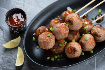 Close-up of nem nuong or fried vietnamese pork sausages on skewers, selective focus, studio shot