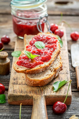 Fruity sandwich with fresh cherry jam on wooden table