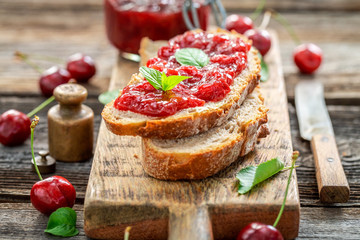 Sandwich with fresh cherry jam on wooden table