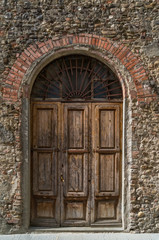 Arch doorway with old wooden door and stone wall