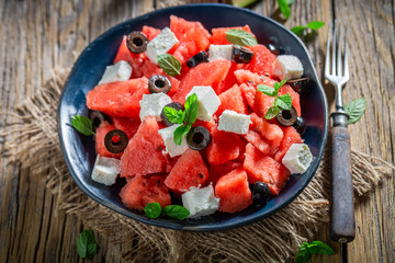 Watermelon salad with olives and feta on wooden table