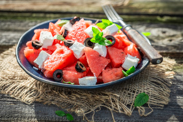 Watermelon salad with feta, olives and mint on rustic table