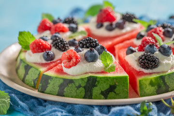 Closeup of watermelon pizza with whipped cream and berry fruits
