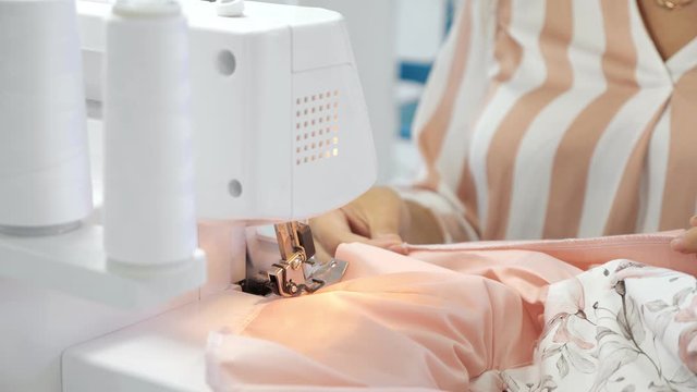 Processing tissue overlock. Seamstress working at sewing workshop sews on overlock cloth edges, close up. Clothing manufacture.