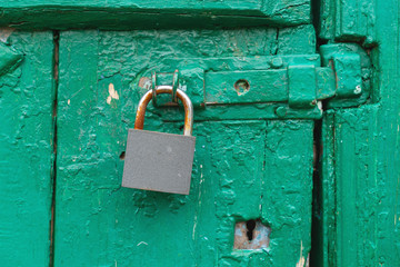hinged metal lock on old green wooden door