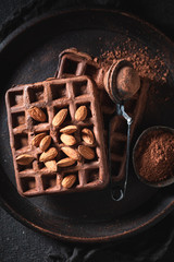 Waffles made of cocoa and nuts on dark table