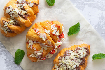 Tasty croissants covered jam and chocilate with cream and strawberry filling on grey cement background.Top view.