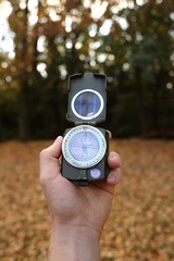 Naklejka premium Autumn concept. Autumn travel.Compass in a male hand in the autumn forest.