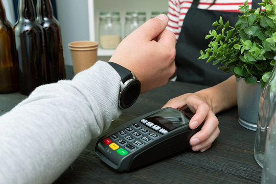 Customer making wireless or contactless payment using smartwatch. Store worker accepting payment with nfc technology