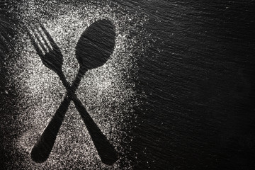 Spoon and fork silhouette made with flour on dark texture background, up horizontal view