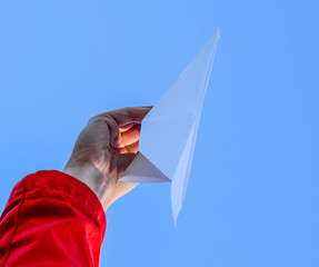 White paper airplane in hand against the sky. A symbol of freedom on the Internet