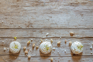 White marshmallows on old wooden background decorated with pistachios Flat lay.