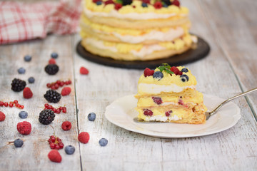 Homemade puff pastry cake with milk cream. Decorated with fresh berries.