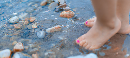 Pies de bebé  en el agua con tierra y piedras
