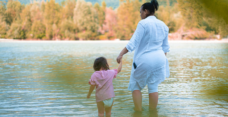 Mama con bebé que camina en el rio