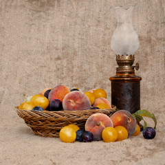 Old fashioned heritage fruit from a long abandoned orchard in an old wicker bowl, with vintage oil lamp on hessian. Still life.